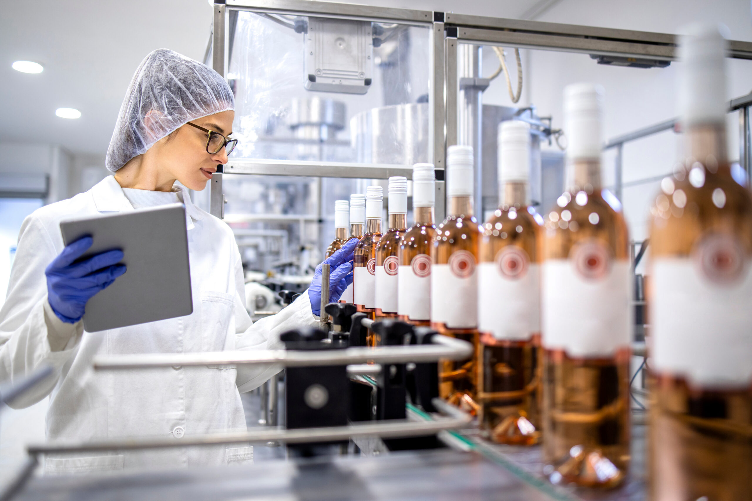 Wine and spirits bottles with customs documents and shipping containers representing TTB alcohol import compliance.