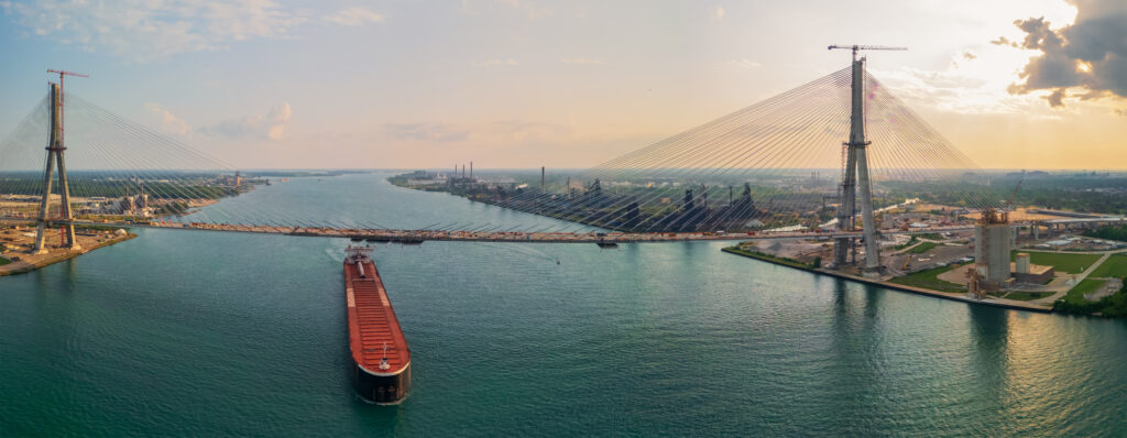 A barge under newly constructed Gordie Howe International Bridge across the USA and Canada border at Detroit downtown. This image has an empty alt attribute; its file name is AdobeStock_927879460-1024x398.jpeg